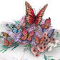 Close-up of colorful butterflies rising above layered purple, pink and white flowers on 3D pop-up card